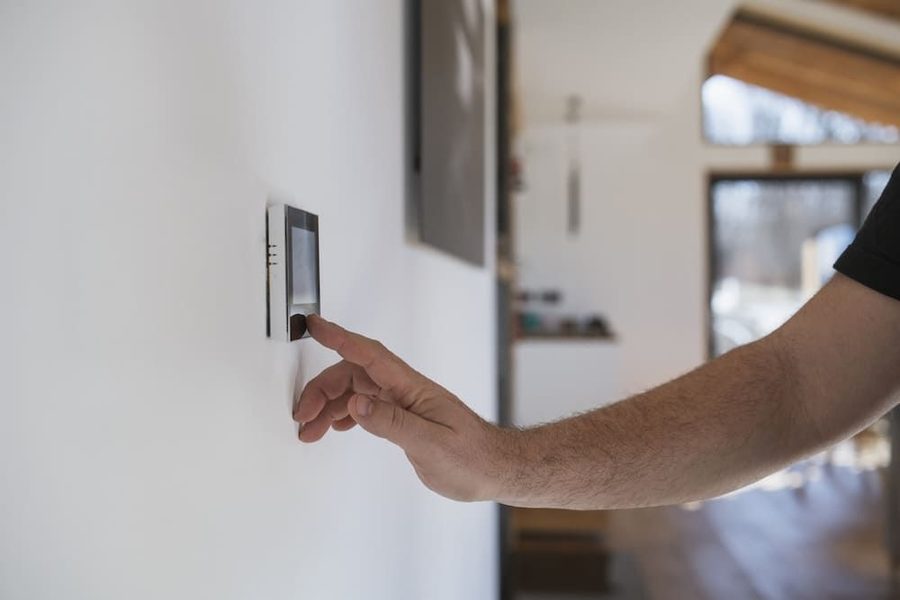 Homeowner adjusting smart thermostat on the wall of his home