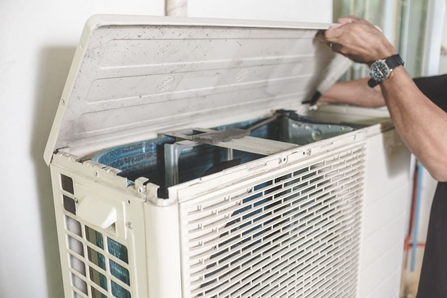 HVAC technician working to repair a heat pump and performing seasonal maintenance